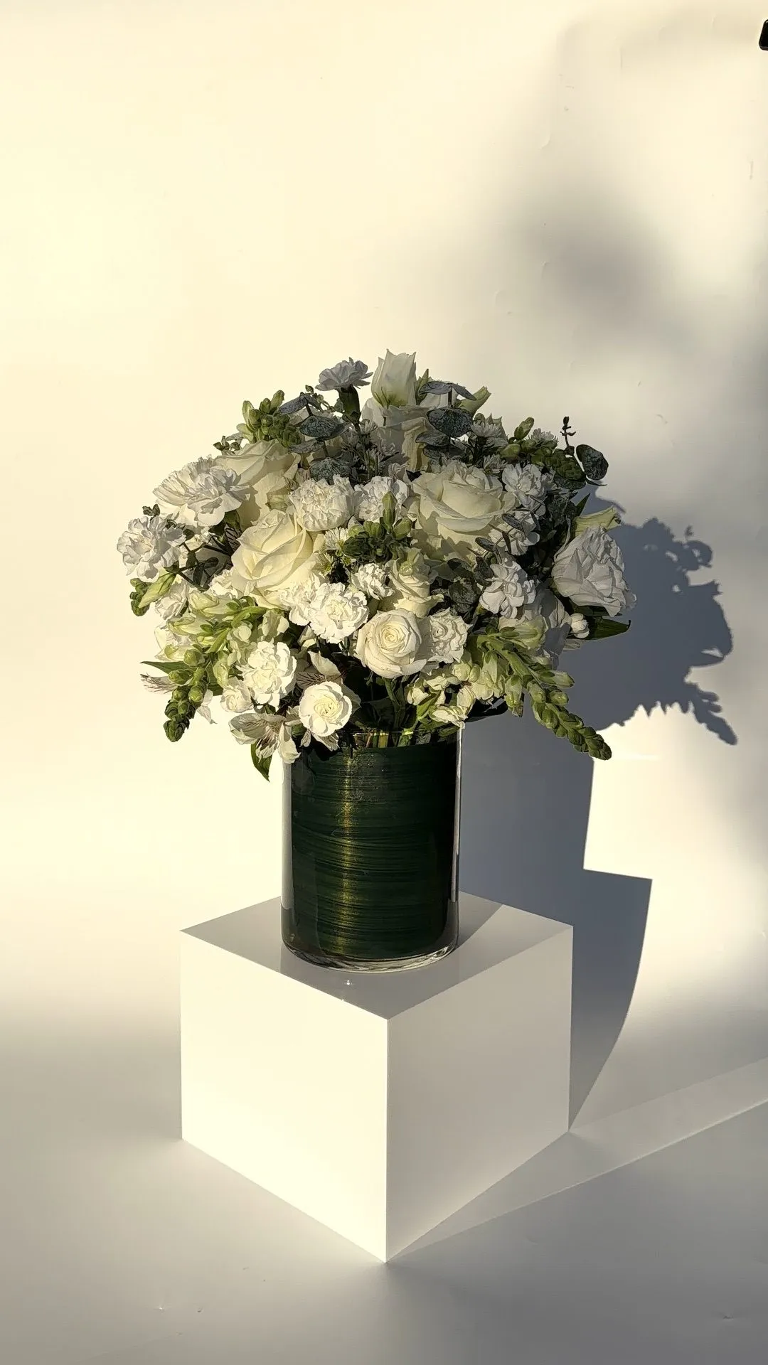 White vase arrangement of roses and carnations built for a memorial service